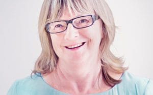 A woman with glasses smiling for the camera.