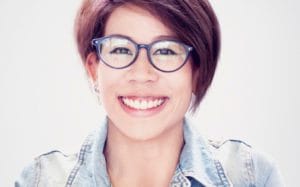 A woman with glasses smiling for the camera.