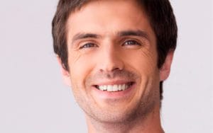 A man with brown hair and blue eyes smiling.