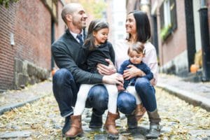 Dr Robert Mirandola and family sitting on the ground in front of some buildings - gonstead family chiropractor