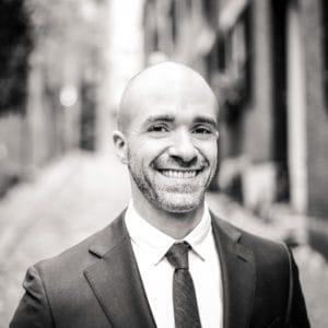 A man in suit and tie smiling for the camera.
