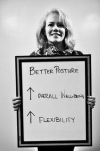 A woman holding up a board with arrows pointing to better posture and overall wellbeing.
