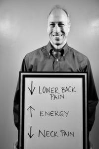 A man holding up a sign with arrows pointing to lower back pain.