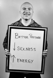 A man holding up a board with the words " sickness " and " better posture ".