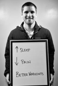 A man holding up a sign with arrows pointing to sleep and pain.