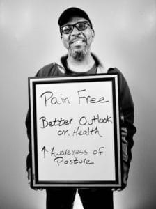 A man holding a sign that says pain free.