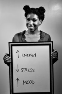 A woman holding up a sign with energy and stress written on it.