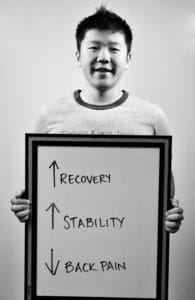 A man holding up a sign with arrows pointing to recovery and stability.