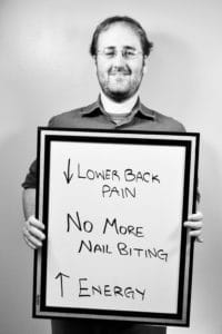 A man holding up a sign that says lower back pain.