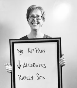 A woman holding up a sign that says no hip pain and allergies.