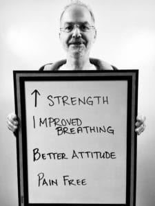 A man standing in front of a sign with words written on it.