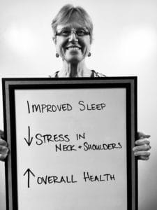 A person holding up a sign that says improved sleep and stress in neck and shoulders.