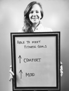 A woman holding up a board with arrows pointing to the center of it.