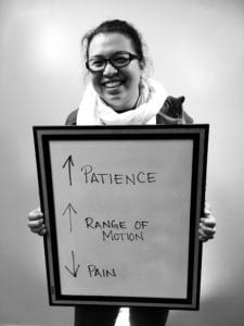 A woman holding up a sign with arrows pointing to the center of patience.