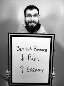 A man holding up a sign with the words " better posture " and " pain action ".