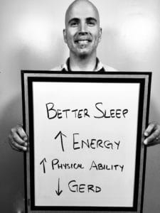 A man holding up a sign that says better sleep, energy and power.