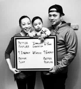 A family holding a sign with the names of their children.