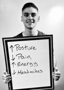 A man holding up a whiteboard with the words " posture " and " pain " written on it.