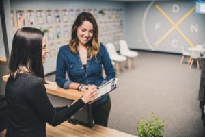 A woman shaking hands with another person in an office.