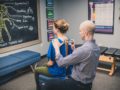 A man and woman sitting in front of a chalkboard.