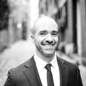 A man in suit and tie smiling for the camera.