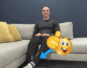 A man sitting on the couch with his foot up.