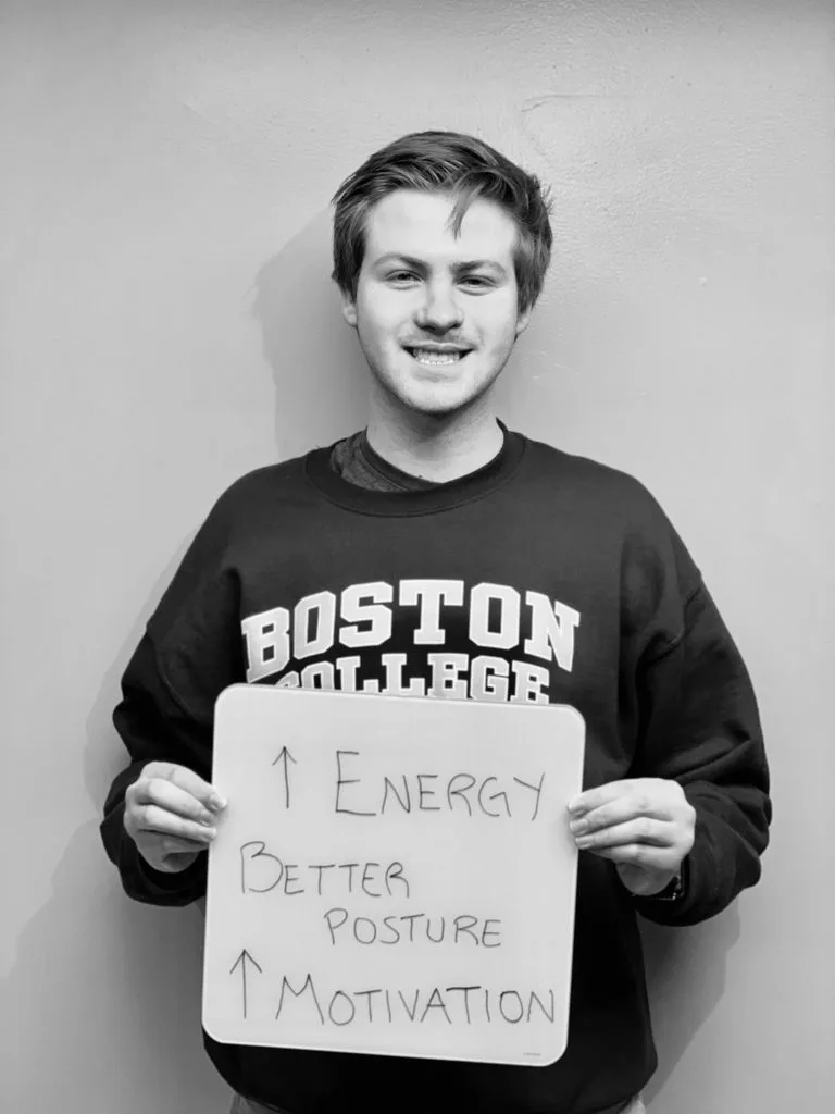 patient story - A man holding up a sign that says improved energy, better posture, improved motivation- neuro-structural chiropractic adjustment results for adults