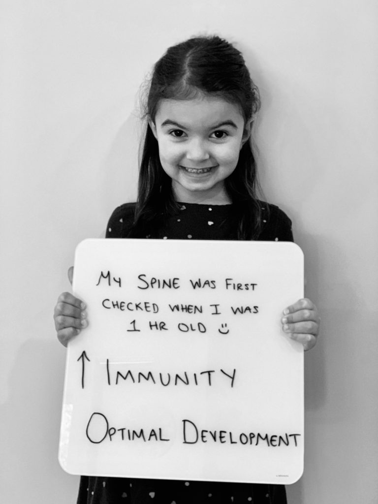 patient story - a little girl holding up a sign that says improved immunity and optimal development - neuro-structural chiropractic adjustment results for children