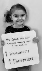 A young girl holding up a sign with the words " my smile was first."