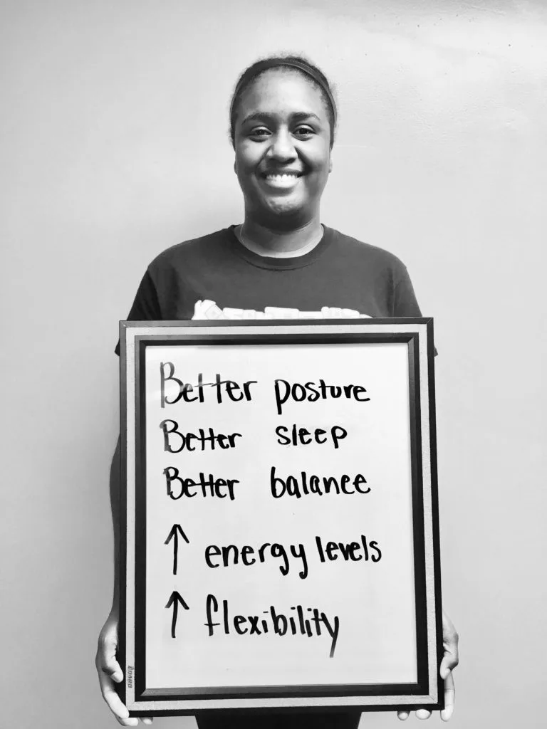 patient story - A woman holding up a sign that says better posture, better sleep, better balance, increased energy levels and increased flexibility - neuro-structural chiropractic adjustment results for adults