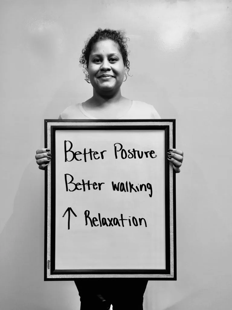 patient story woman holding up sign that says - better posture, better walking, and improved relaxation - neuro-structural chiropractic adjustment results for adults