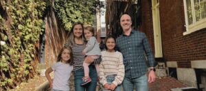 A family posing for a picture in front of some trees.