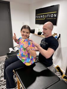young girl smiling and thumbs up at The Foundation Chiropractic office - pediatric chiropractic care