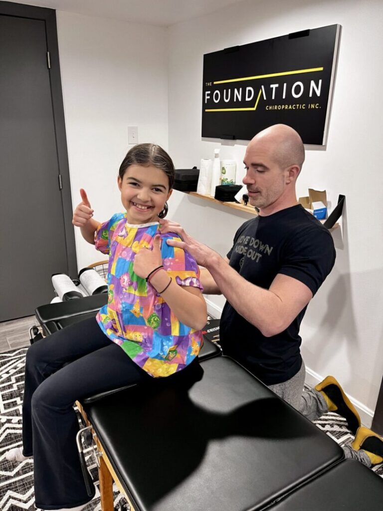 young girl smiling and thumbs up at The Foundation Chiropractic office - pediatric chiropractic care