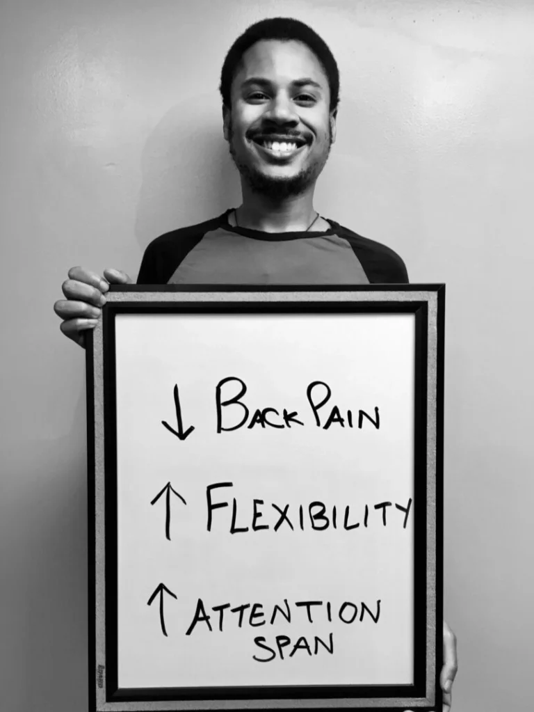 patient story - man holding a sign that says reduced back pain, more flexibility and increased attention - neuro-structural chiropractic adjustment results