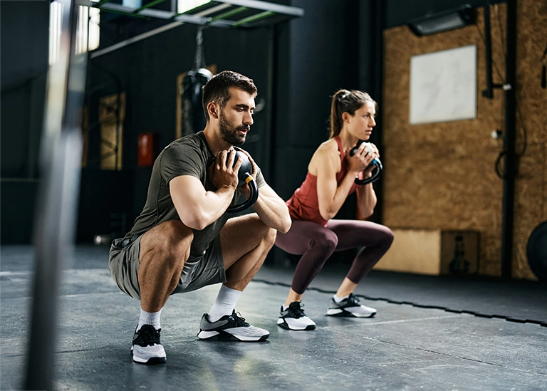 two athletes at the gym squatting and doing crossfit - chiropractic care for athletes