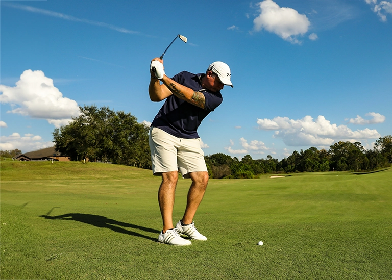 golfer swinging his golf club on a green course- chiropractic care for athletes