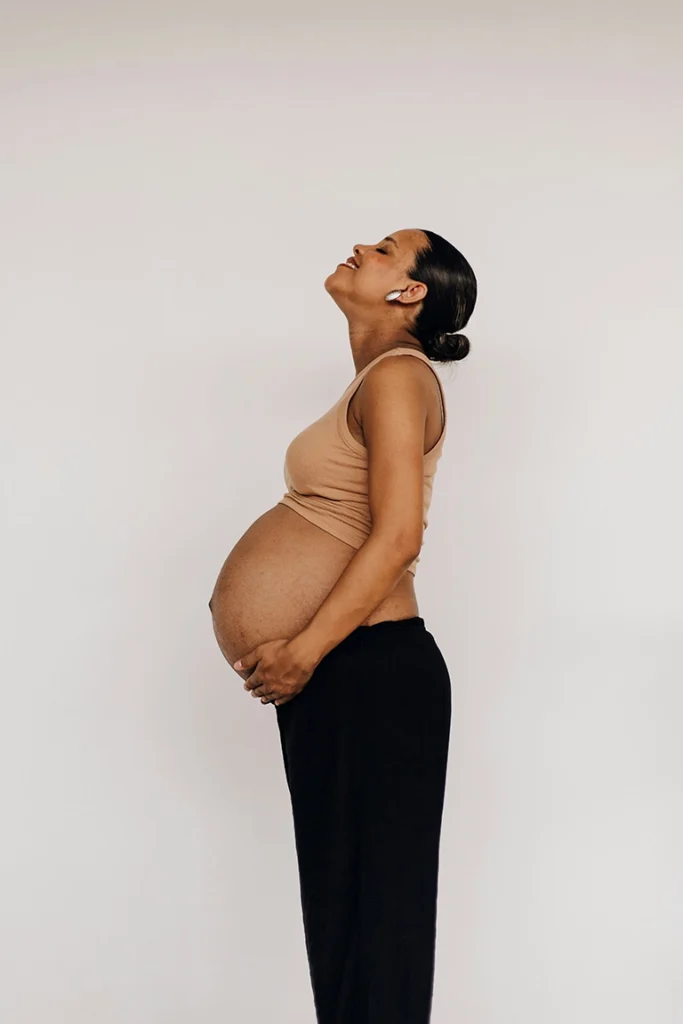 pregnant woman smiling and holding her belly - chiropractic care for pregnancy comfort