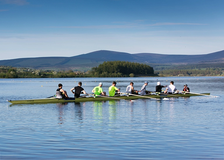 rowers- rowing team paddings on a long boat on the water -chiropractic care for athletes
